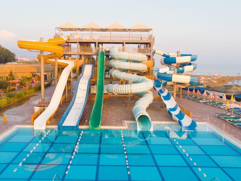 Velká barevná vodní skluzavka u hotelového bazénu pod jasnou oblohou.