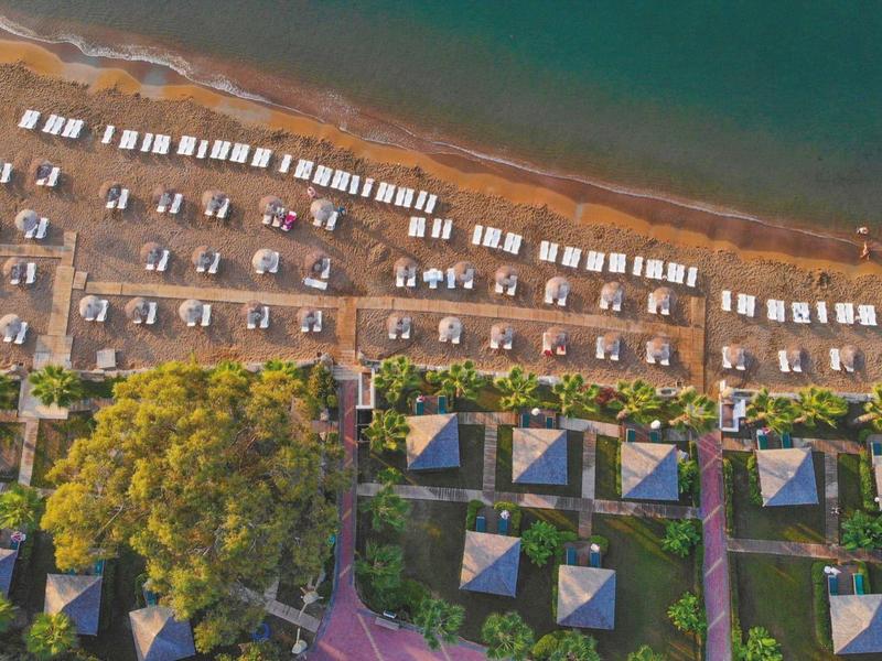 Letecký pohled na pláž s uspořádanými slunečníky a řadami lehátek.