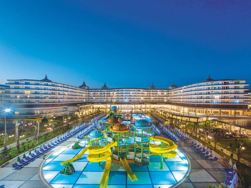 Moderní hotelový komplex se světelně osvětlenými vodními skluzavkami v noci.