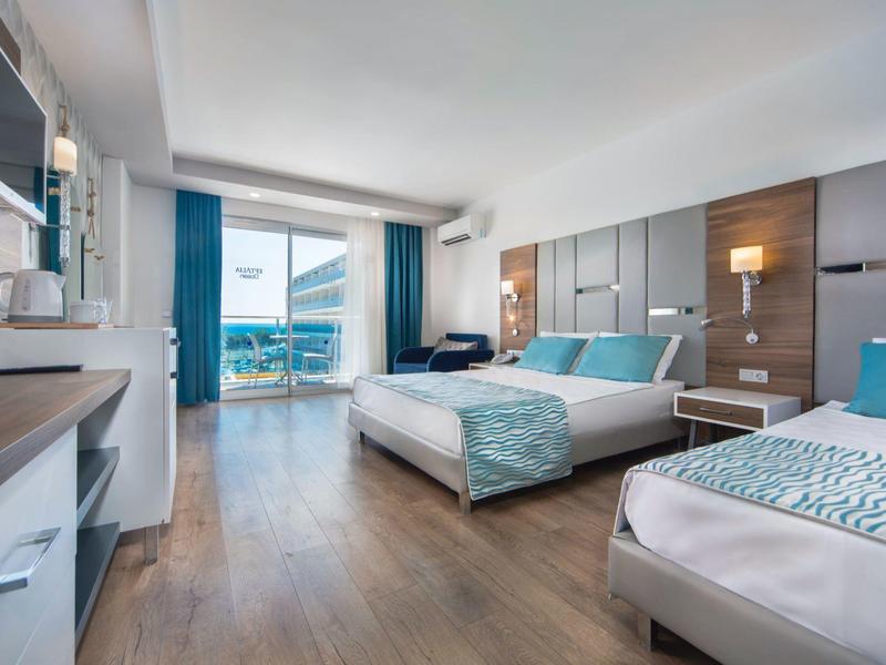 Moderní hotelový pokoj se dvěma postelemi, dřevěnou podlahou a výhledem na balkon s mořem.