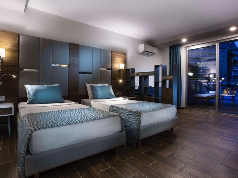 Moderní hotelový pokoj se dvěma jednolůžky a výhledem na město přes velké okno.