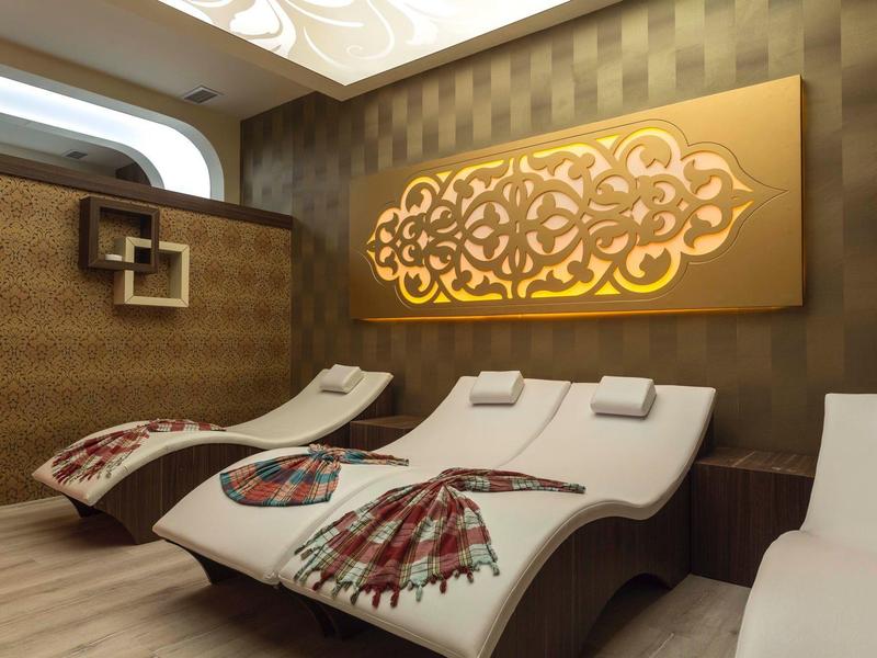 Relax zóna s zakřivenými lehátky a zlatou dekorací na zdi.