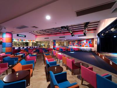 Duża przestrzeń eventowa z kolorowymi siedzeniami i sceną, idealna na pokazy i imprezy.