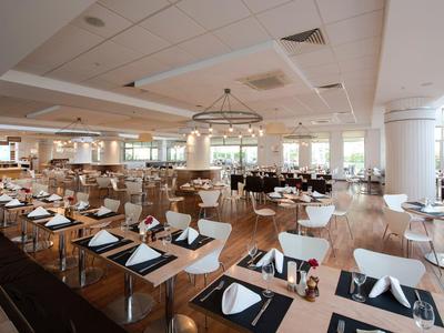 Przestronna, jasna jadalnia z drewnianymi krzesłami i nakrytymi stołami w nowoczesnym stylu.