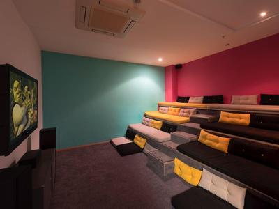 Małe kino domowe z piętrowymi siedzeniami, kolorowymi ścianami i dużym ekranem.