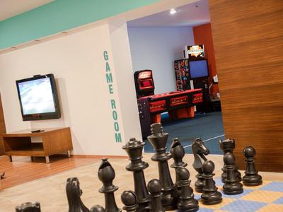 Duży zestaw szachów na podłodze przed pokojem gier z automatami do pinballa.