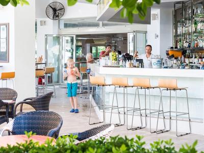 Jasny bar hotelowy z nowoczesnym wystrojem i zrelaksowanymi gośćmi wewnątrz.