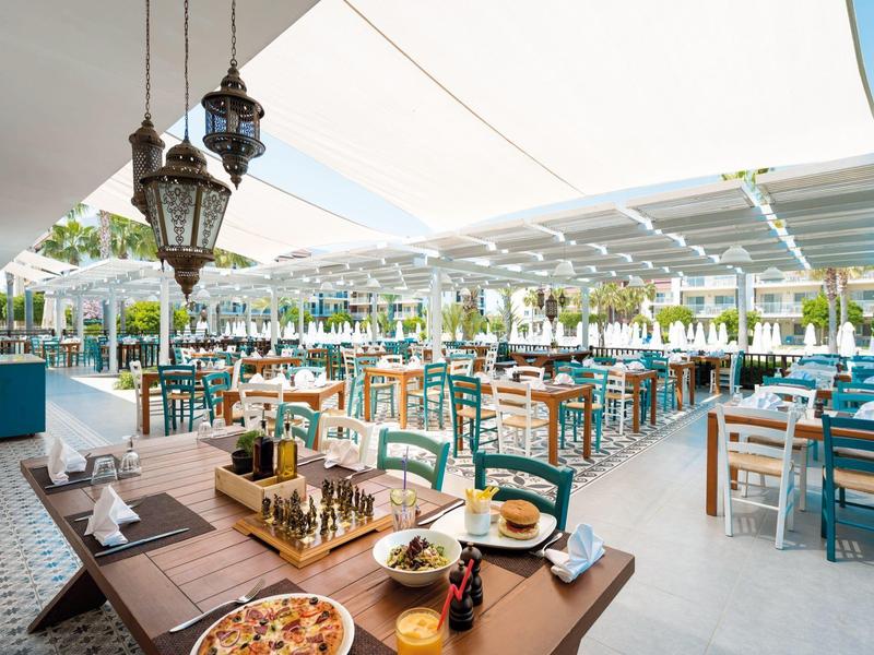 Jasna, zadaszona restauracja z kolorowymi krzesłami i nakrytymi stołami na zewnątrz.