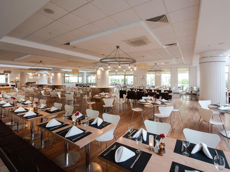 Przestronna, jasna jadalnia z drewnianymi krzesłami i nakrytymi stołami w nowoczesnym stylu.