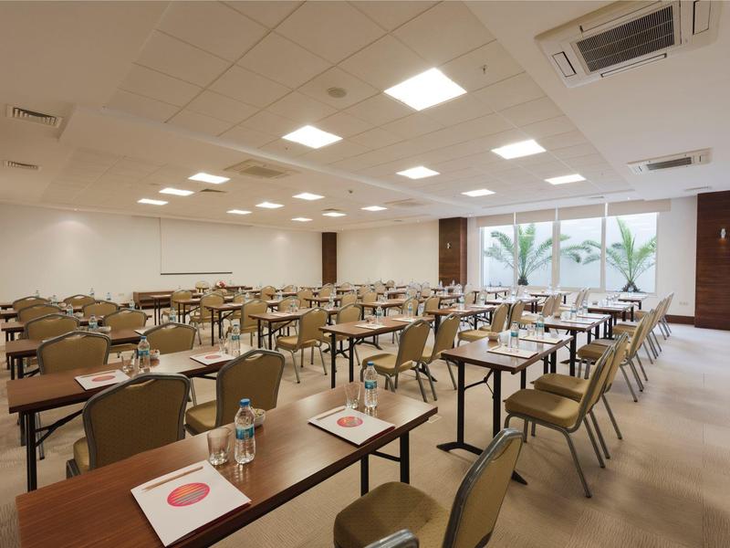 Duża, jasna sala konferencyjna z wieloma stołami i krzesłami, przygotowana na wydarzenie.