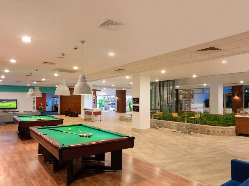 Wnętrze hotelu z bilardem, miejscami do siedzenia i nowoczesnym oświetleniem.