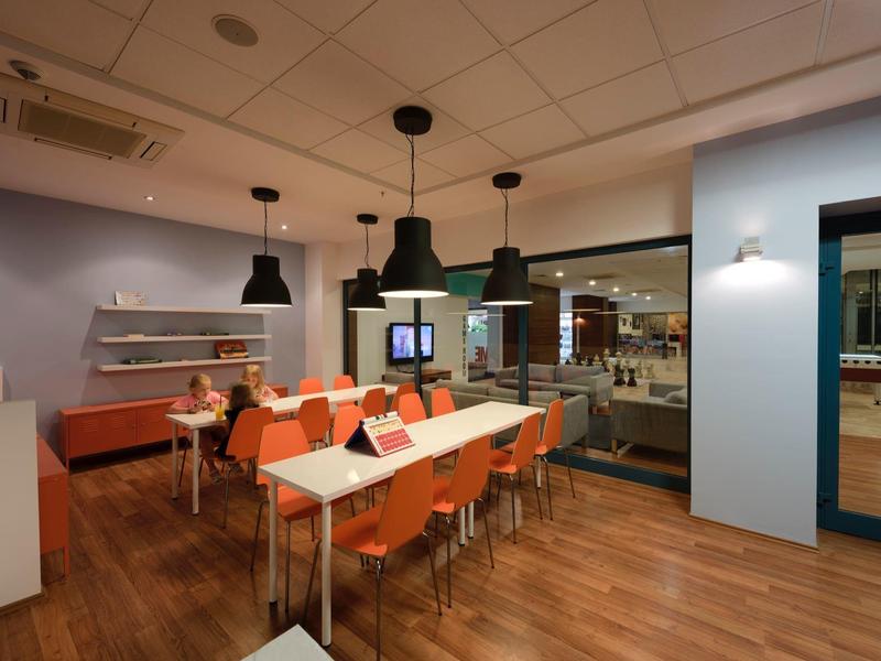 Nowoczesna sala spotkań z drewnianą podłogą, pomarańczowymi krzesłami i dużymi oknami