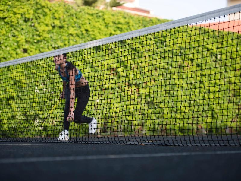 Kobieta przygotowująca się do serwisu podczas meczu tenisa na zewnątrz.