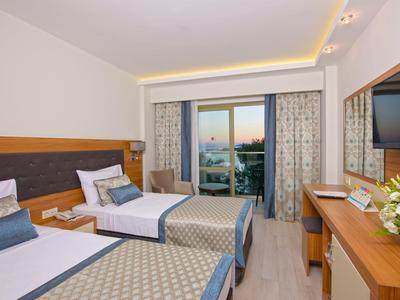 Modernes Hotelzimmer mit zwei Einzelbetten, Balkon, Flachbildfernseher und Holzmöbeln.