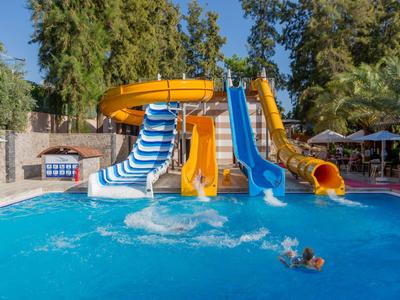 Toboggans aquatiques colorés et piscine avec des enfants jouant sous un ciel bleu clair en plein air