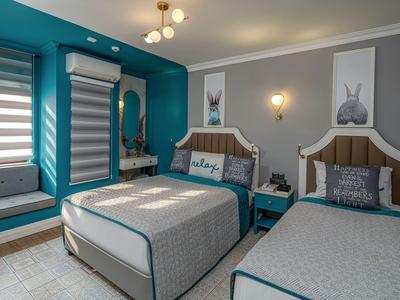 Deux lits simples dans une chambre d'hôtel élégante avec des murs bleus et un siège près de la fenêtre.