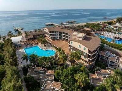 Hôtel de luxe avec grandes piscines et vue sur la mer, entouré de palmiers et jardins.