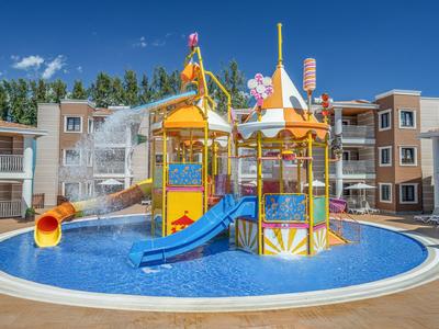 Parque acuático infantil con toboganes y juegos de agua en piscina de hotel en un día soleado.