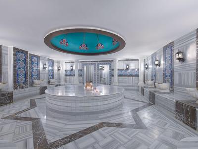 Espacioso hammam turco con revestimiento de mármol, azulejos azules y ambiente acogedor.