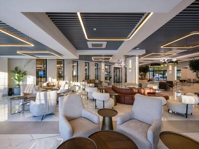 Área elegante del vestíbulo del hotel con sillones cómodos, mesas y diseño moderno en tonos neutros.