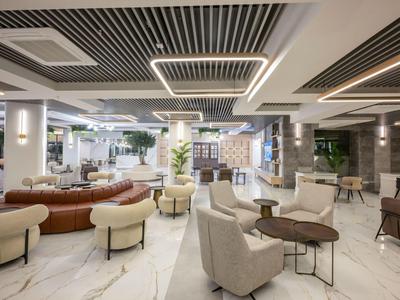 Moderna zona de lounge de hotel con muebles elegantes y suelo de mármol claro.