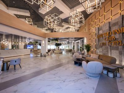 Moderna recepción de hotel con elegante suelo de mármol, asientos elegantes y decoraciones geométricas en el techo.
