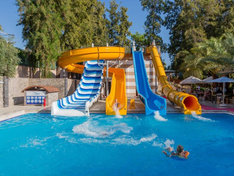 Toboggans aquatiques colorés et piscine avec des enfants jouant sous un ciel bleu clair en plein air