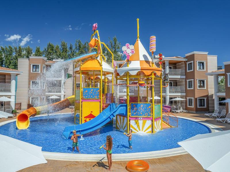 Parc aquatique avec toboggan coloré et aire de jeux dans la piscine d'un hôtel par jour ensoleillé.