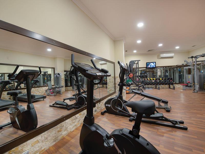 Salle de sport moderne avec équipements d'entraînement et grands miroirs sous un éclairage lumineux.