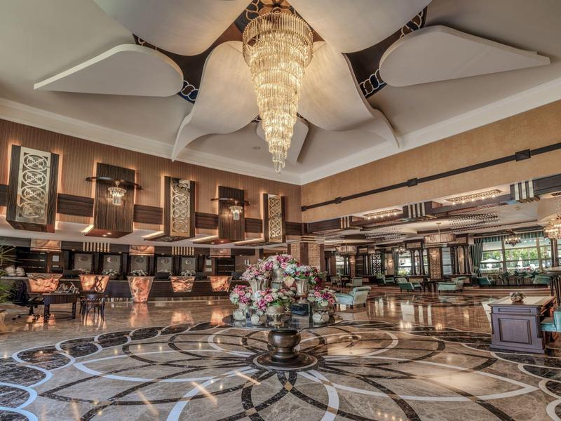 Hall d'hôtel élégant avec lustre, bar et arrangement floral sur sol en pierre.