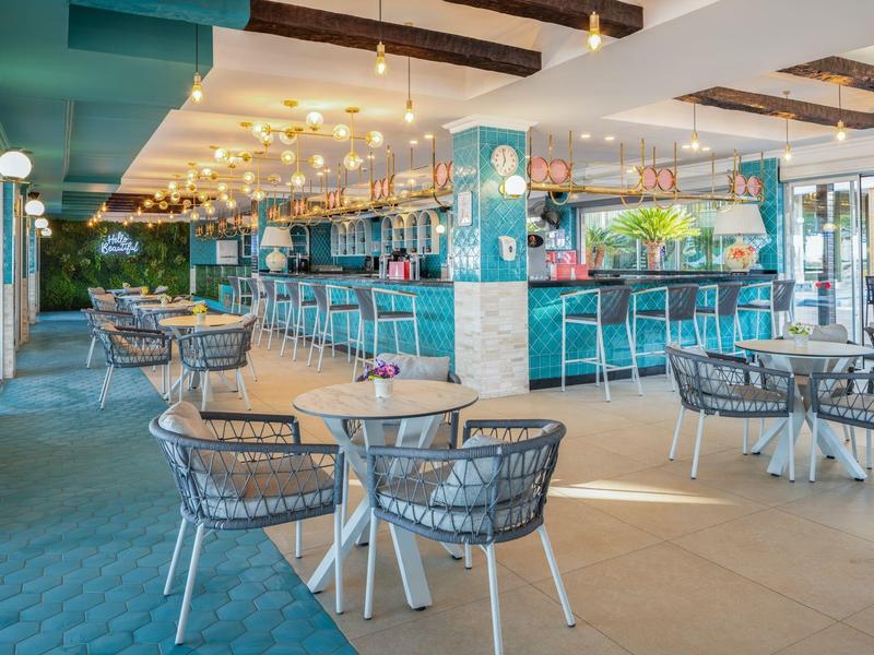 Restaurant lumineux avec murs bleus, espaces assis et lumières décoratives au plafond.