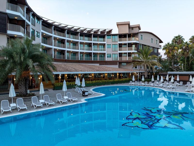 Hôtel avec grande piscine extérieure, chaises longues et parasols dans un cadre tropical