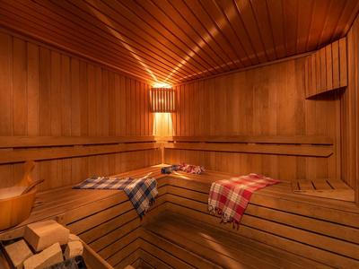 Wood sauna with illuminated wall lamp and checkered towels on the bench.