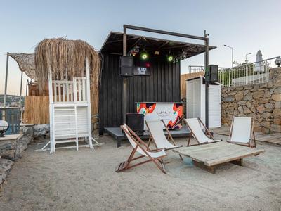 Beach bar with deck chairs, beach volleyball net, and sand in a relaxed setting.