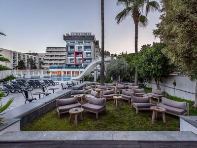 Modern outdoor area with seating and pool in front of a multi-story hotel building.