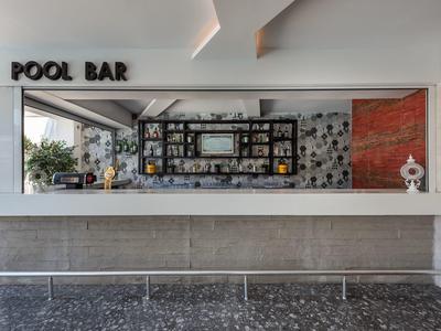 Modern pool bar with mosaic wall and shelves with bottles behind the counter.