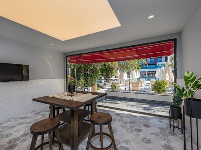 Modern interior with wooden table and bar stools in front of large window overlooking garden.