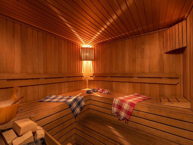 Wood sauna with illuminated wall lamp and checkered towels on the bench.