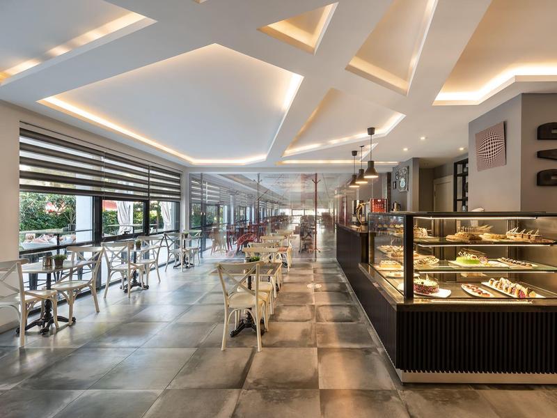 Modern café with display cases, counter, and seating area overlooking outside.