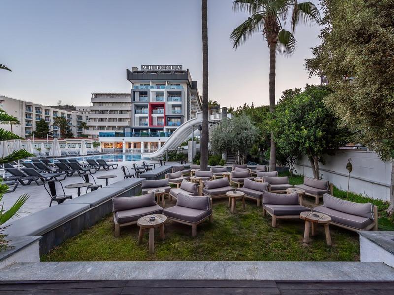 Modern outdoor area with seating and pool in front of a multi-story hotel building.