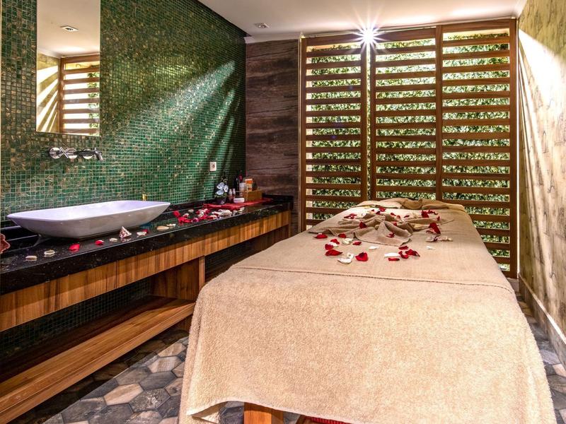 Interior of a luxurious massage room with a treatment table and decorative flower petals.