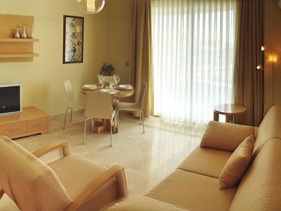 Sala luminosa con sofá, televisor y gran ventana con cortinas para ambiente acogedor.