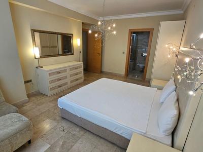 Habitación de hotel moderna con cama doble, sillón y luz clara.