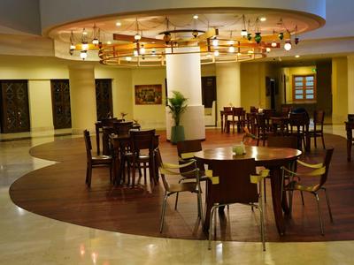 Área de salón elegante en hotel con mesas redondas y lámparas cálidas y acogedoras.