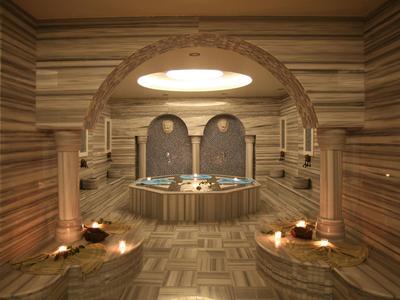 Área de spa lujosa con jacuzzi bajo un arco decorativo y luz cálida