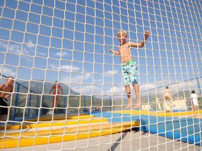 Kind springt op een trampoline buiten onder een heldere hemel.