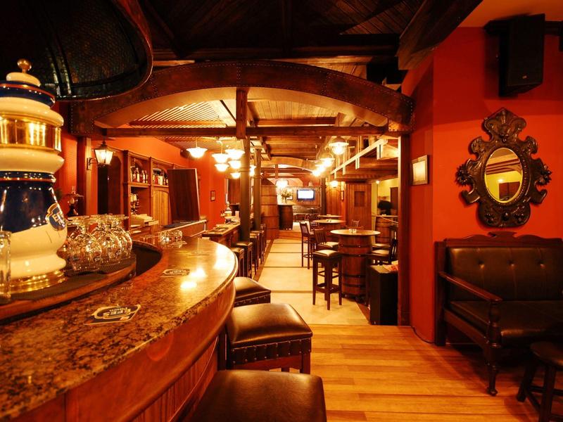 Acogedora sala de hotel con interior cálido de madera y área de bar con asientos.