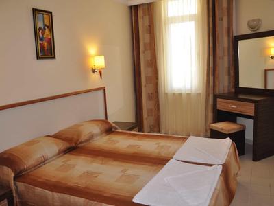 Chambre d'hôtel avec deux lits simples, grand miroir et tons bruns chauds.