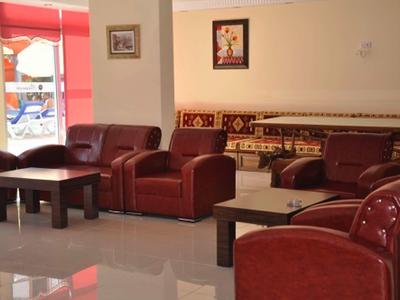 Espace lounge confortable avec fauteuils en cuir rouge et tables en bois dans un hôtel