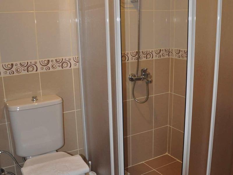 Salle de bain compacte avec toilettes et cabine de douche à portes battantes.